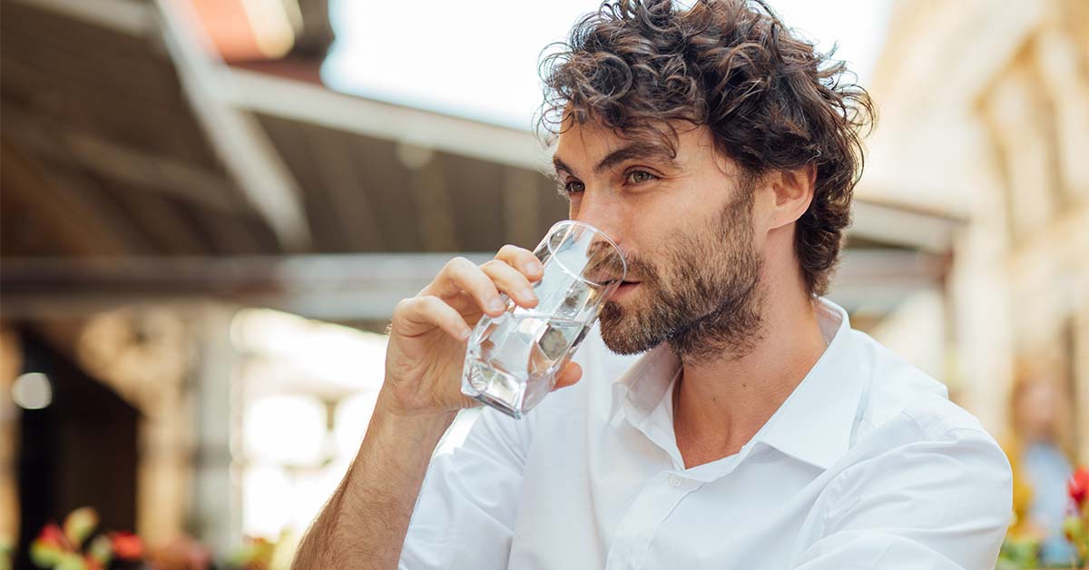 Man outside drinking a glass of water.