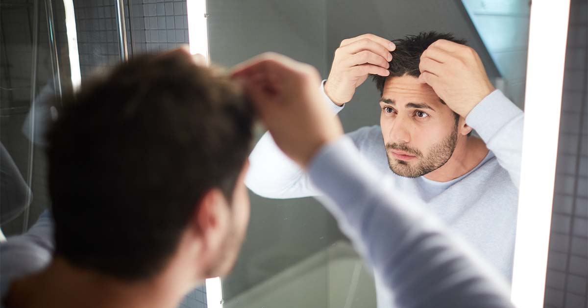 Man checking hairline in mirror.
