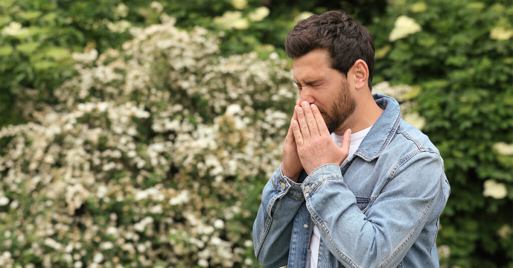 Man outside sneezing
