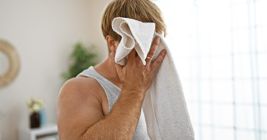 Blond man towel drying his face